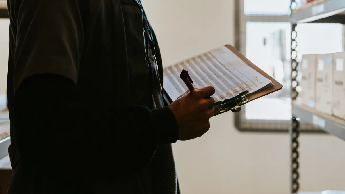Person writing on a clipboard indoors
